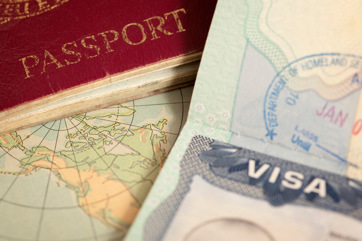 A passport and visa are sitting on top of a map.